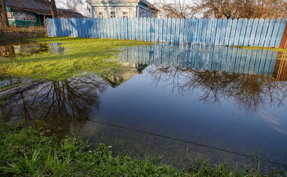 Blue fence surrounds a flooded yard