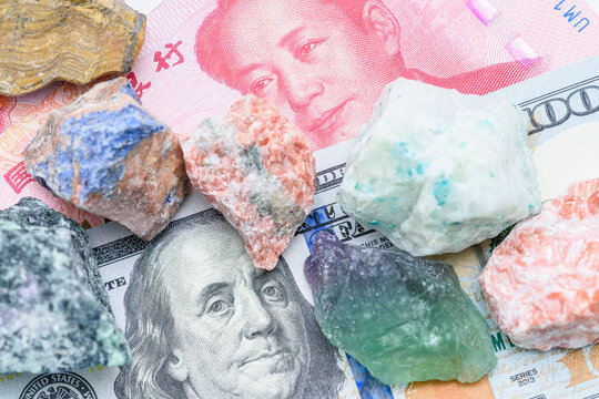 Macro view of raw mineral ore on US $ and Chinese &yen; banknotes, illustrating critical-minerals dependency, trade shifts and investment opportunities in raw-materials.