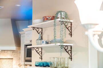 A lovely kitchen with three shelves and an elegant wall lamp