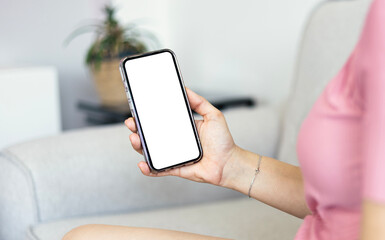 Close up woman hand holding a smartphone blank white screen	and sitting at home