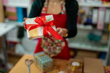 Woman presenting christmas gift with red ribbon