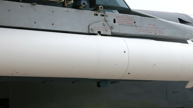 Soviet era aerial missile mounted under fighter jet wing, cold war military technology detail, closeup view of aircraft weapon system