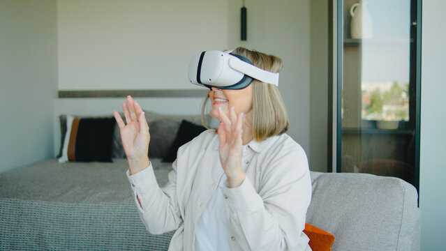 Elderly woman enjoying virtual reality experience in modern living room with cheerful demeanor during afternoon