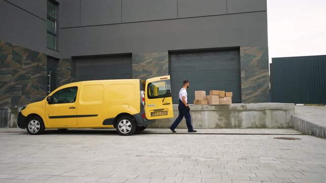 Delivery driver unloading cardboard boxes from yellow van