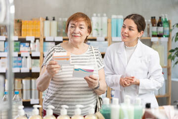Qualified pharmacist makes recommendations to a mature female buyer when choosing medicines and pills. Buyer chooses headache pills
