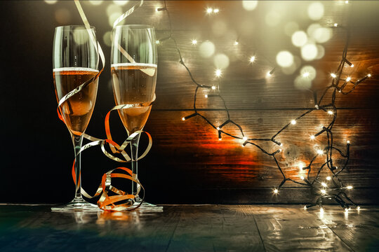 two champagne glasses with ribbons against holiday lights and fireworks - New Year celebrations