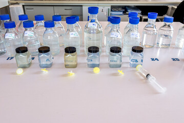 Laboratory storage bottles with blue polypropylene cap and plastic bottles on white table.