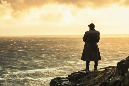 A solitary figure in a long coat stands on a cliff edge, contemplating the vast, turbulent sea under a dramatic, golden sky.