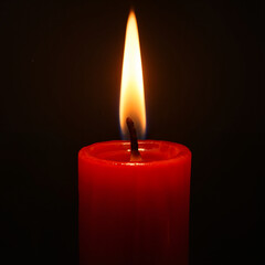 Red candle burning with a flame against a black background  
