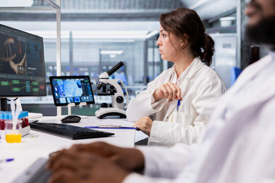 Researcher looking at 3D molecular model visualization on computer monitor in biotechnology laboratory. Bioinformatics scientist using bioengineering software on PC in medical lab displaying DNA data