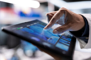 Naklejka premium Close up of tablet used by male scientist for molecular biology samples, working in chemistry lab. Experiment showcases innovation in genetics research and nanotechnology, healthcare solutions.