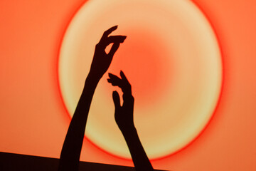 Hands reaching towards a glowing circle on a vibrant red and orange background during a creative event