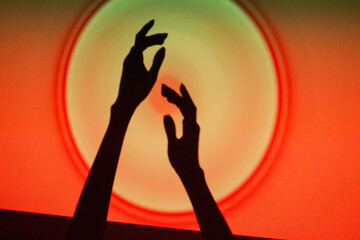 Hands reaching towards a glowing circle on a vibrant red and orange background during a creative...