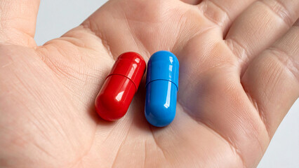 Human hand holding red and blue capsules symbolizing choice, decision, and future medical innovation
