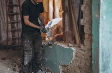 A young man destroys a brick wall using a sledgehammer.