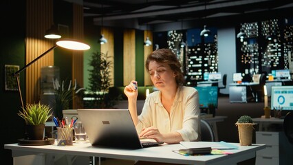 Businesswoman wondering about possible solutions to a dilemma with laptop at desk, intense...