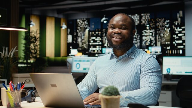 Portrait of male worker immersed in reading emails and researching data for a multinational company, working after hours in a dark office. Focusing on objectives for development.