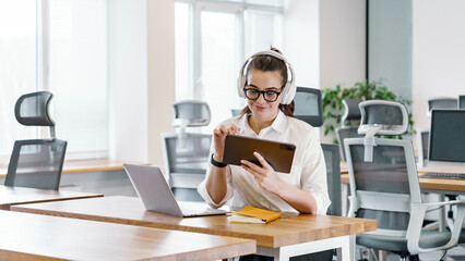 Young woman using tablet in modern office space while seated at table