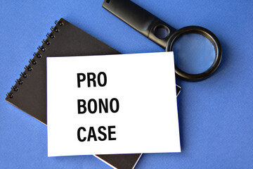 PRO BONO CASE - words on a white sheet on a black notebook with a magnifying glass