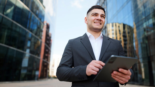 Businessman using a tablet in an urban environment surrounded by glass buildings