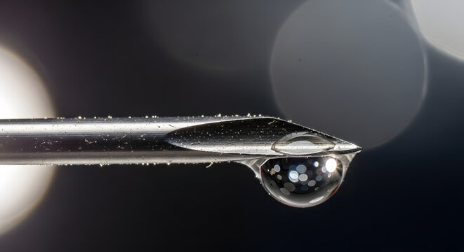 macro shot of hypodermic needle tip with liquid droplet