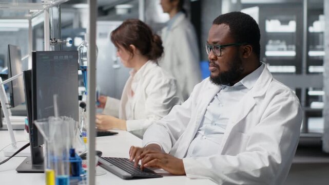 Scientist in laboratory interprets clinical blood values on computer monitor during study. Research facility worker doing sanguine fluid analysis, looking at healthcare insights report on PC, camera B