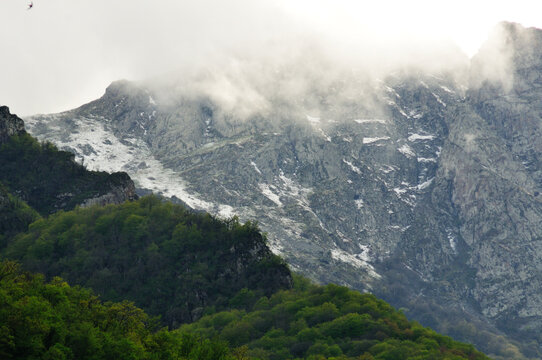 Spring mist over a rocky mountainside with fresh snow