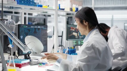Scientist uses laboratory lamp to examine test subject in petri dish. Research facility technician holds medical container to light source, monitoring samples for impurity detection, camera B