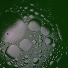 Una toma de cerca de una fondo abstracto  de  varias burbujas en agua y aceite en movimiento en un fondo de color verde oscuro con  algo de desenfoque