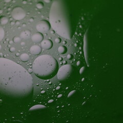 Una toma de cerca de una fondo abstracto  de  varias burbujas en agua y aceite en movimiento en un fondo de color verde oscuro con  algo de desenfoque