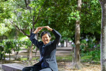 夜の公園でOKサインを示すサラリーマン