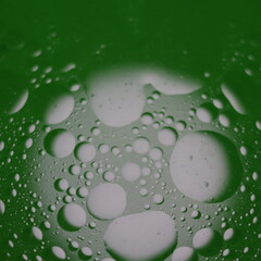 Una toma de cerca de una fondo abstracto  de  varias burbujas en agua y aceite en movimiento en un fondo de color verde oscuro con  algo de desenfoque