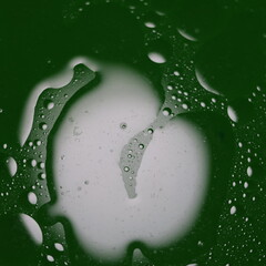 Una toma de cerca de una fondo abstracto  de  varias burbujas en agua y aceite en movimiento en un fondo de color verde oscuro con  algo de desenfoque