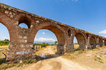 Fototapeta premium Historic Skopje Aqueduct Bridge in North Macedonia against a blue sky. Ancient bridge with arches and masonry.