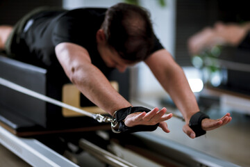 Engaging in a focused workout on reformer pilates machines in a well-lit studio during a morning session