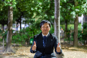 ベンチで親指を立てる笑顔のサラリーマン