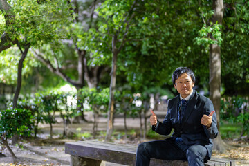 夜の公園でグッドサインをするビジネスマン