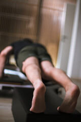 Man performing an advanced exercise on a reformer pilates machine in a modern studio during a morning workout session