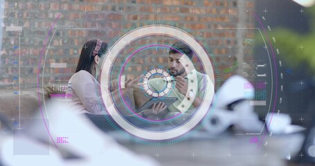 Discussing Hispanic woman and Indian man examining tablet on sofa in lounge, with interface overlay
