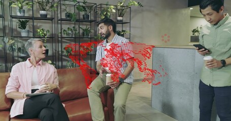 Chatting colleagues sharing coffee cups on leather sofa in office lounge, with tablet phone shelves