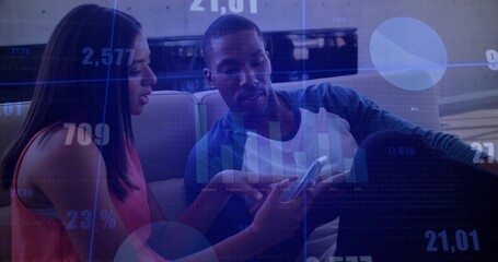 Reviewing charts on phone by coworkers wearing pink and green shirts on leather couch in lounge