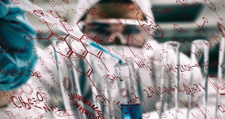 Writing chemist in lab coat drawing structures on glass board in lab, with red formulas