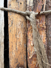 Close-up of rustic wooden logs tied with thick rope, showing natural textures of aged wood and bark, creating an organic and rugged composition.