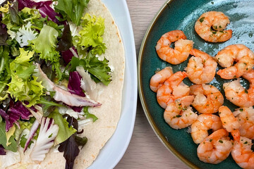 Shrimps with salad and tortilla on wooden table, top view