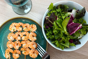 Shrimps with lettuce salad in a blue bowl on a wooden table