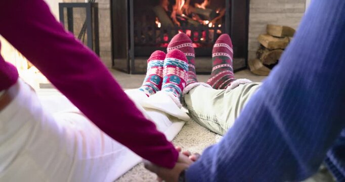 Camera panning upward as couple interlacing fingers on rug, lifting torsos and gazing at fireplace
