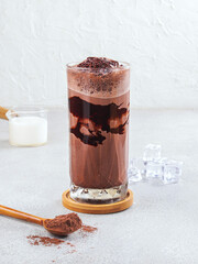 Iced Chocolate Drink with Cocoa Powder and Chocolate Syrup in a Glass – Refreshing Cold Beverage on Gray Background– Refreshing Sweet Beverage