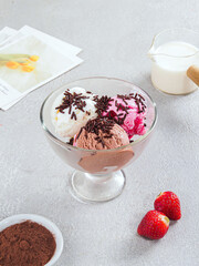 Trio Ice Cream Scoops with Chocolate Sprinkles and Fresh Strawberries – Delicious Dessert in Glass Bowl. Mixed Flavor Ice Cream Dessert – Vanilla, Chocolate, and Strawberry