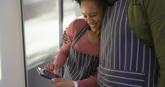 Diverse couple holding smartphone at kitchen island showing gingerbread cookies greeting friend
