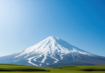 Fototapeta premium Symmetrical snow covered mount fuji towering over rolling green hills in japan.
